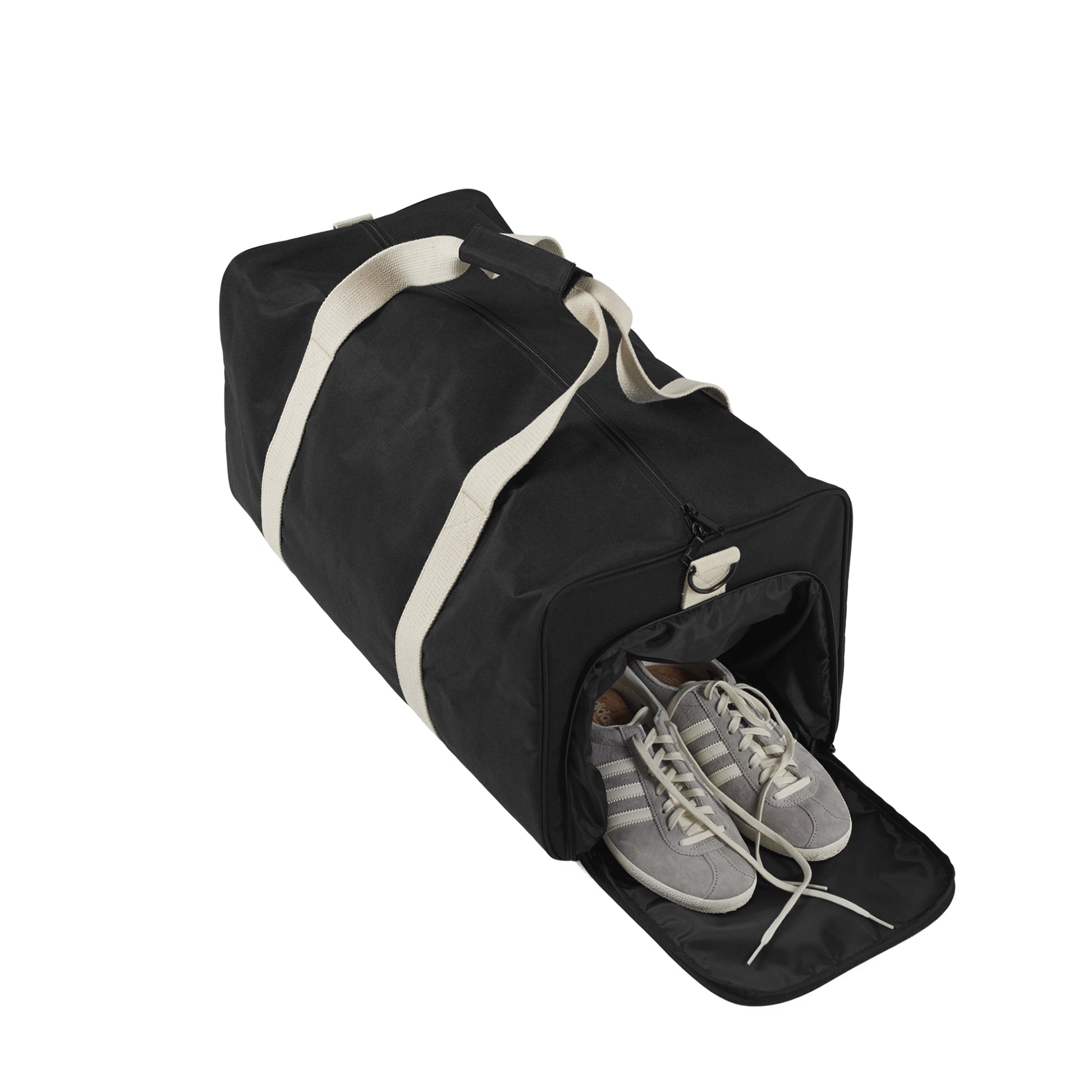 Black duffel bag with white trim containing a pair of gray sneakers on a white background